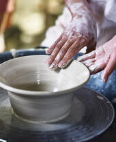 Woman making pottery bowl on a pottery wheel.
