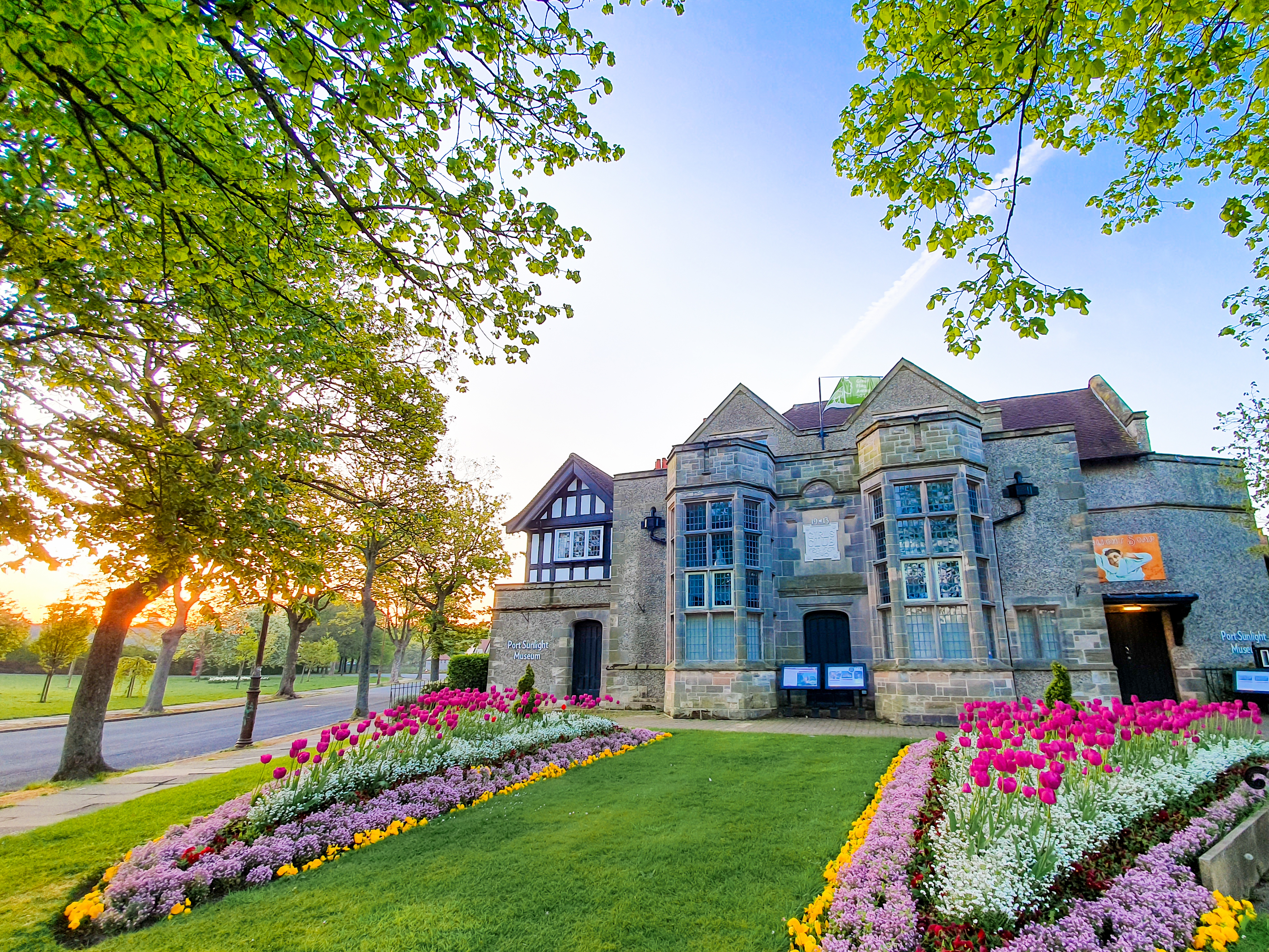 Historic house surrounded by trees and a garden in bloom