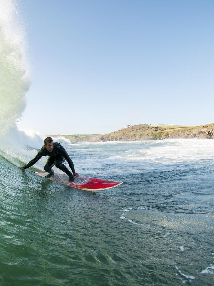 Surfer in a wetsuit surfing a large wave on a red surfboard in the sea