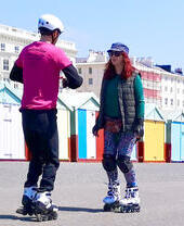 Two people rollerskating along the street in Brighton