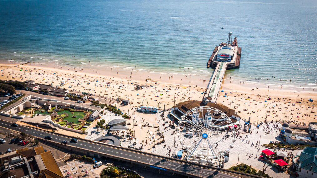 Aerial view of Bournemouth Pier looking out to sea with beach full of people