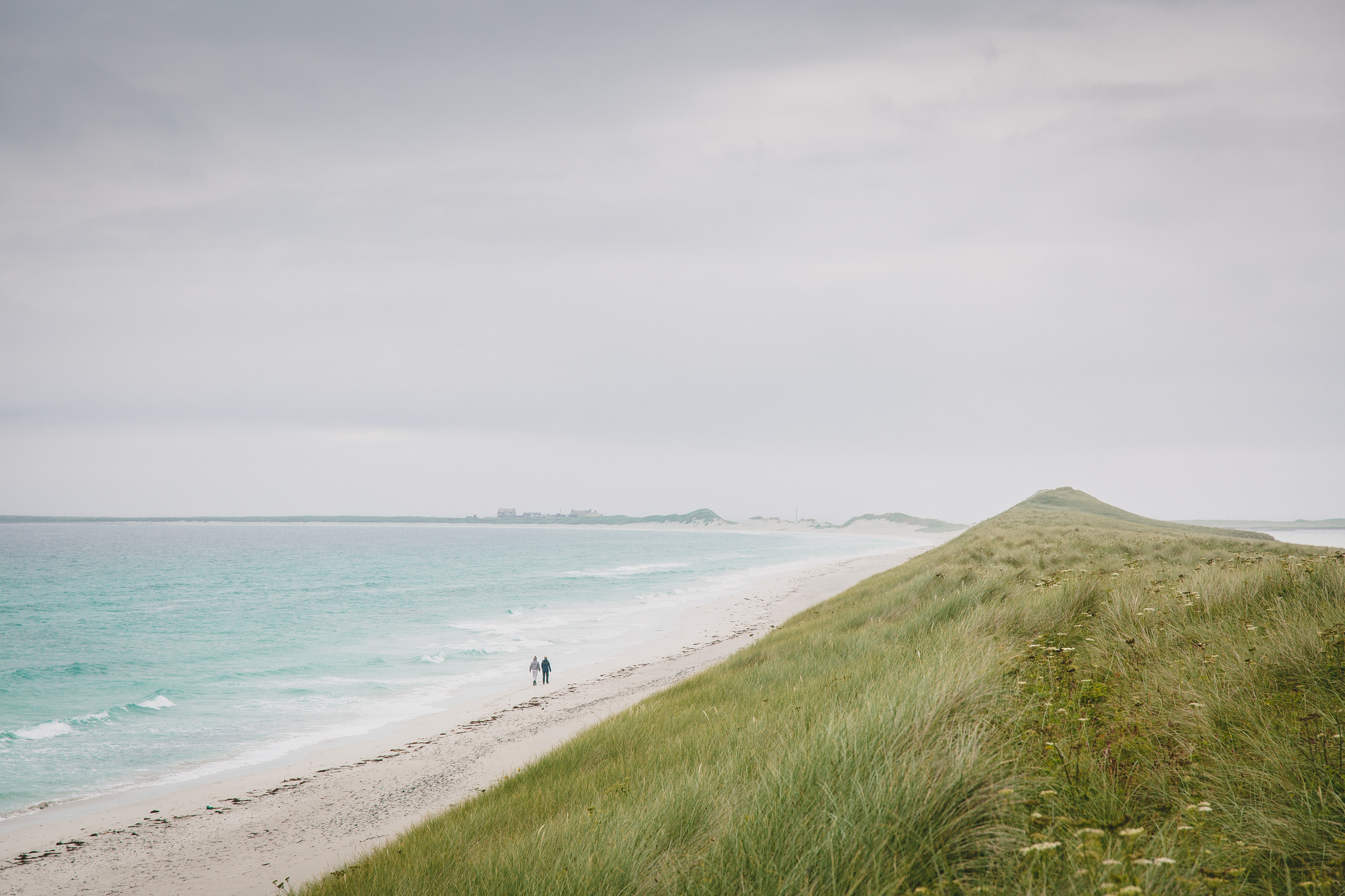 Due persone che camminano lungo una grande spiaggia deserta, Tresness Sanday, Orkney