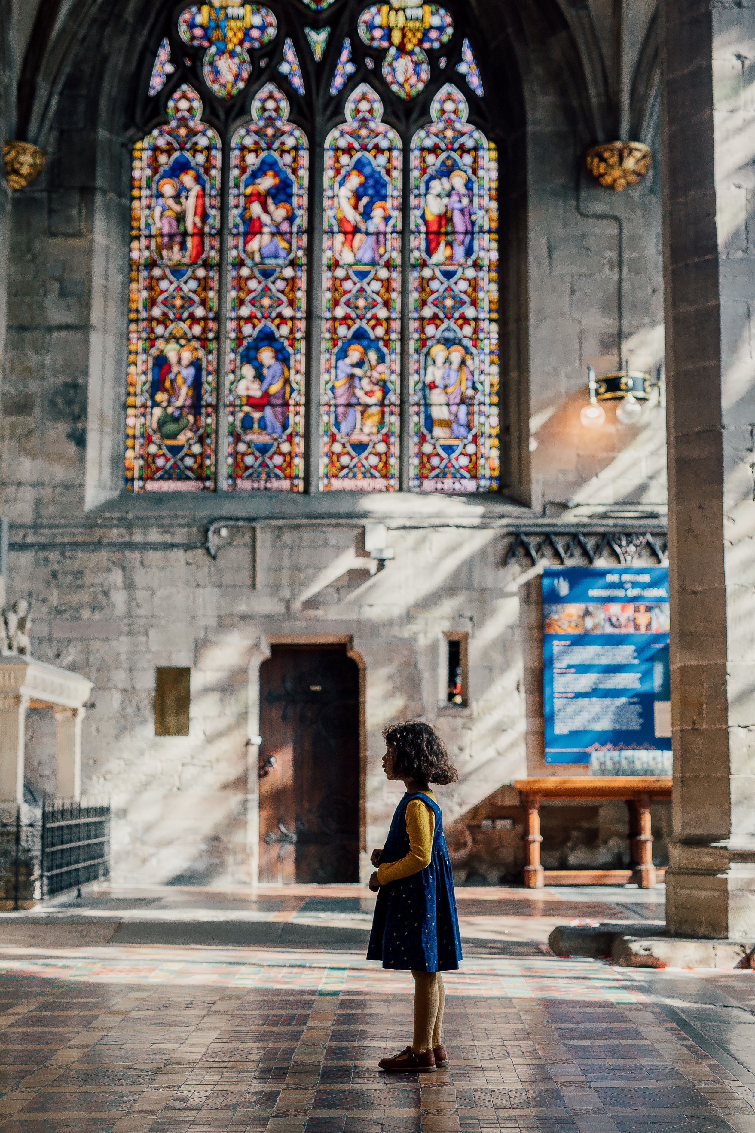 A girl standing in front of a stained glass window in a cathedral