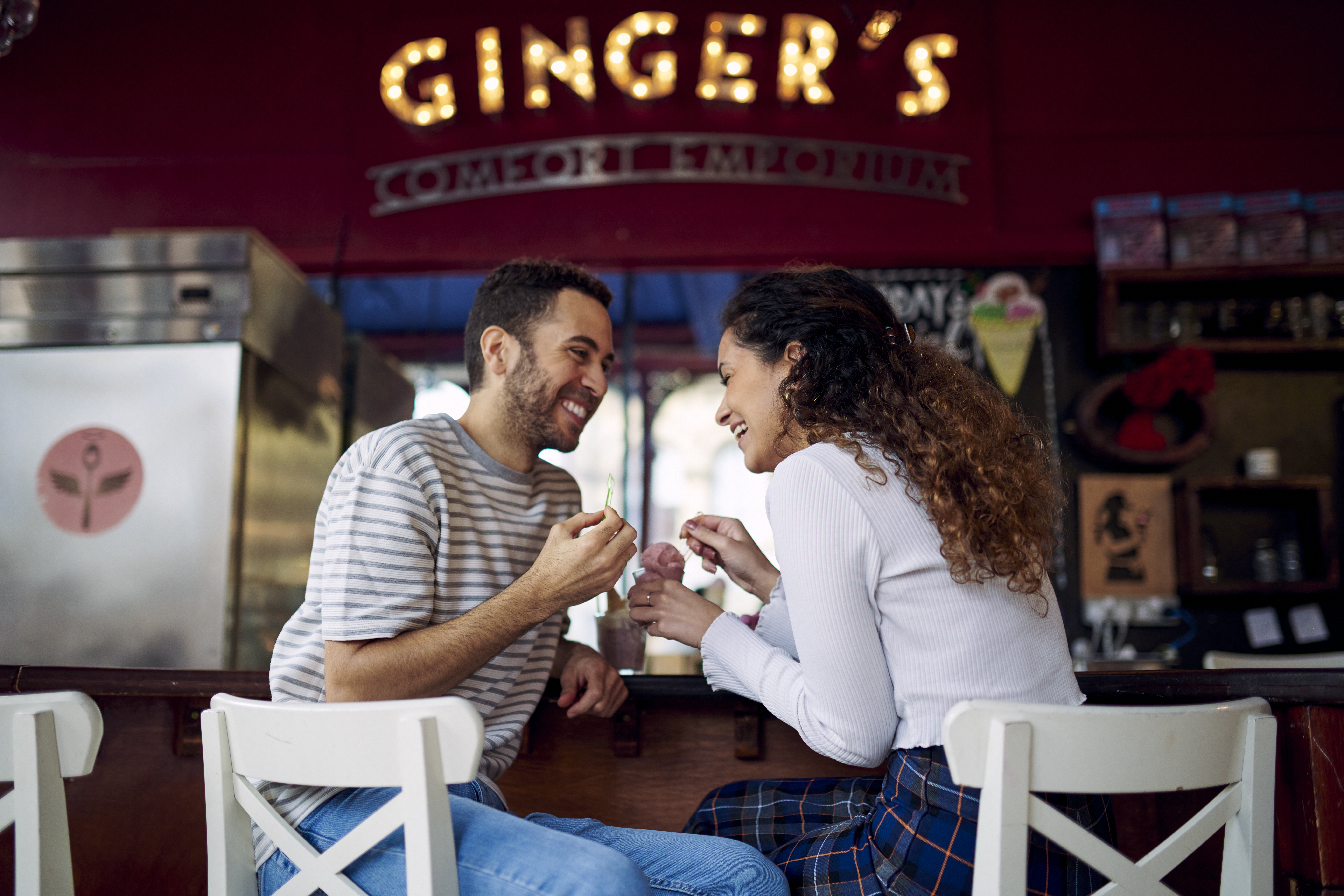 زوجان يجلسان في حانة، يضحكان ويأكلان الآيس كريم في مقهى
