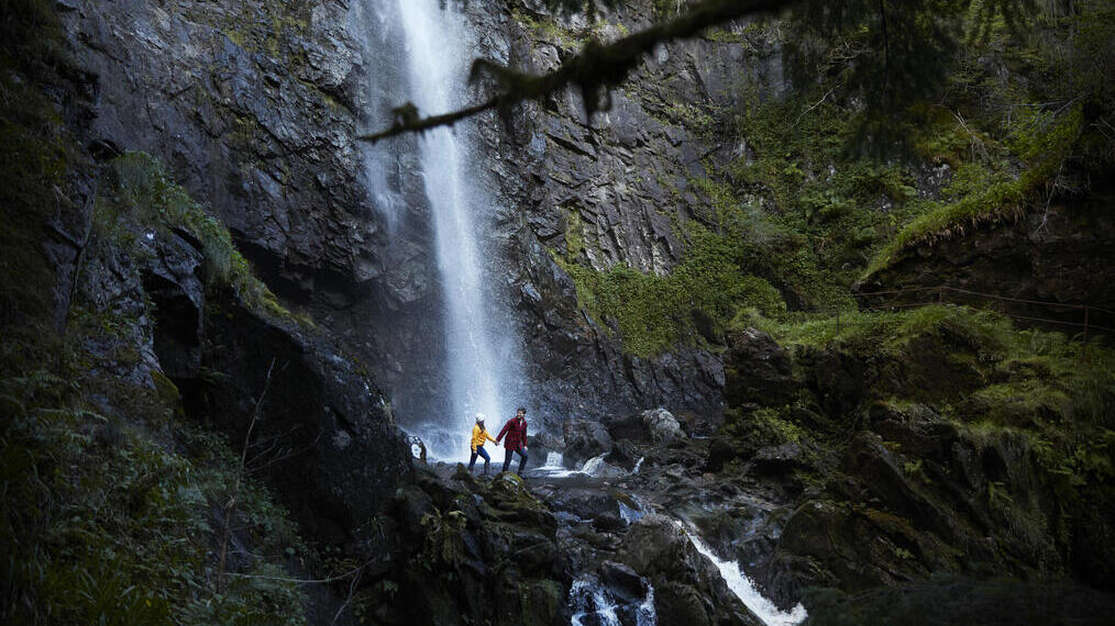 Deux personnes se tenant la main marchant au bord d'une cascade