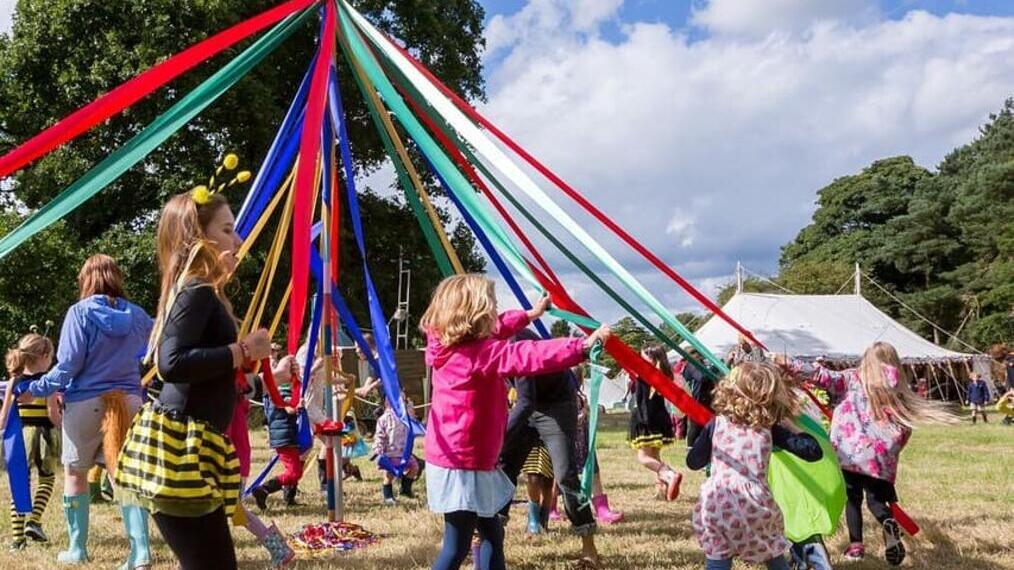 A group of children dancing around a maypole at Hever Castle