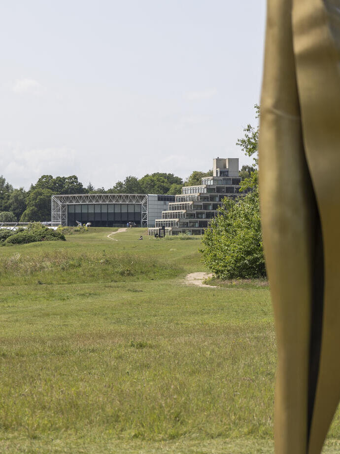 An external shot of a field with a modern building in the background
