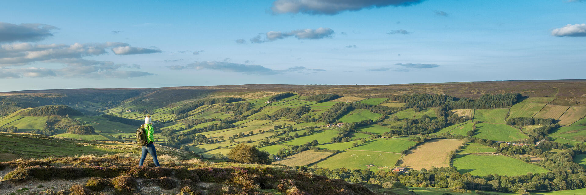 Eine Frau spaziert einen Pfad entlang auf einem Hügel und genießt die Aussicht.
