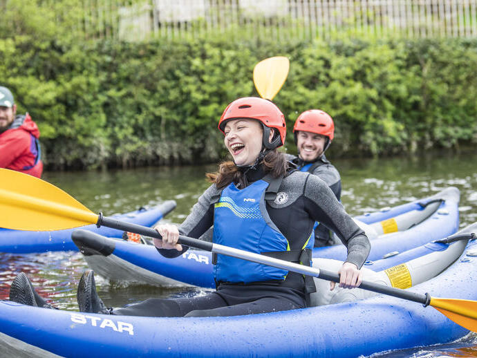 Des gens souriant et riant pendant une descente en kayak sur une rivière à Chester
