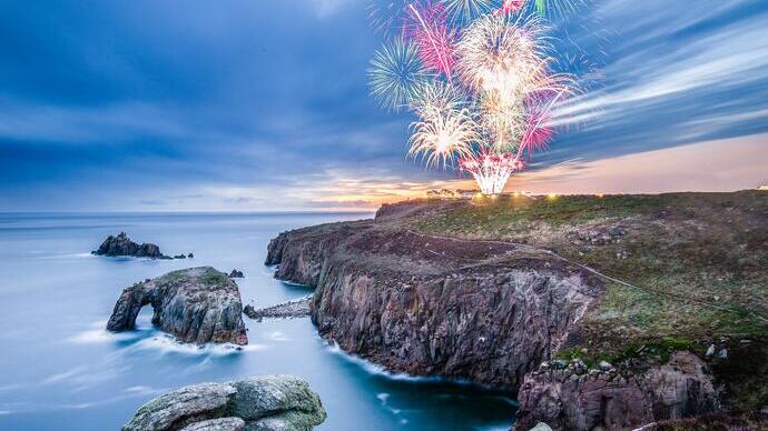 Feuerwerk, gesehen von einer felsigen Landzunge in der Dämmerung