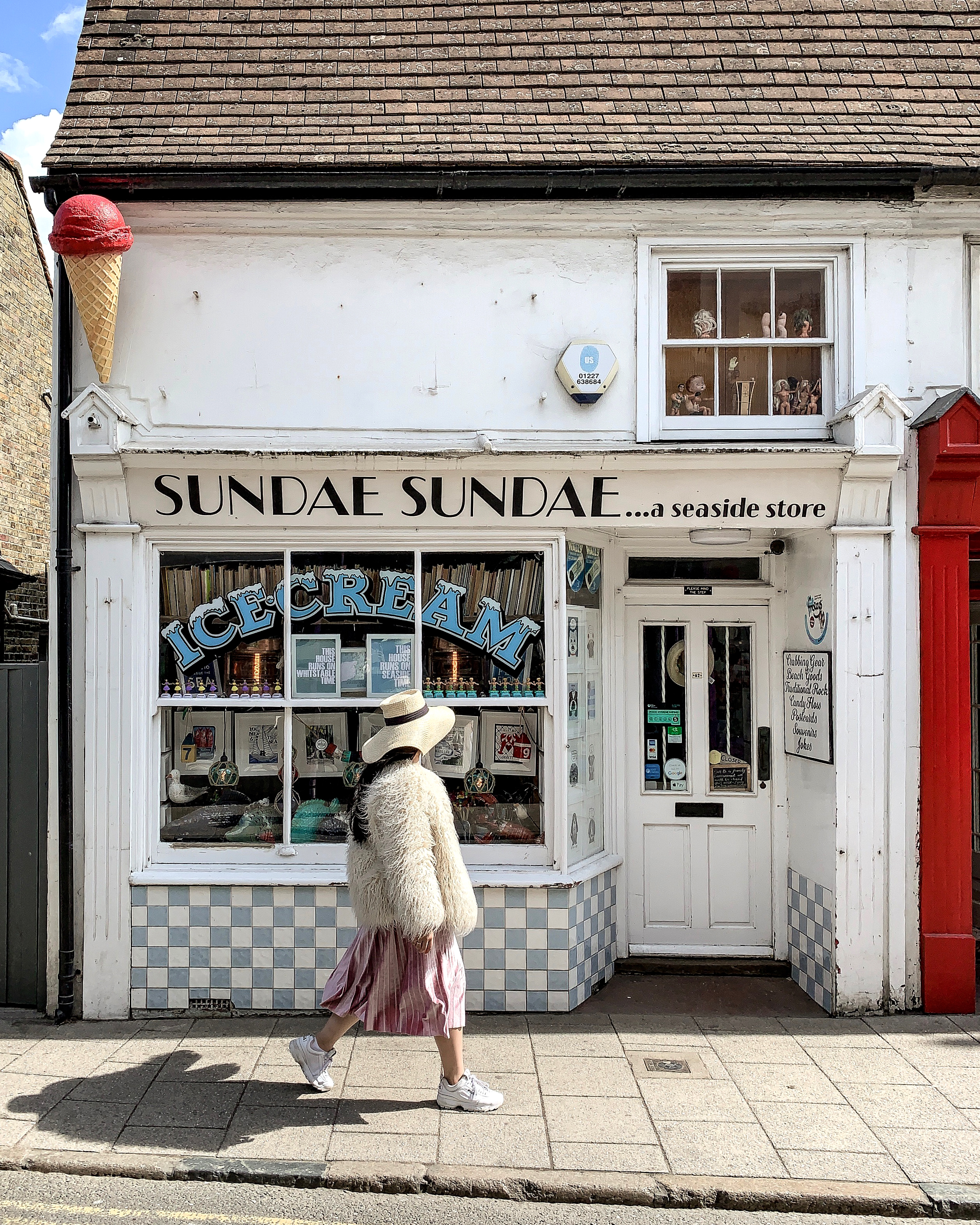 Young woman walking in front of seaside ice cream shop