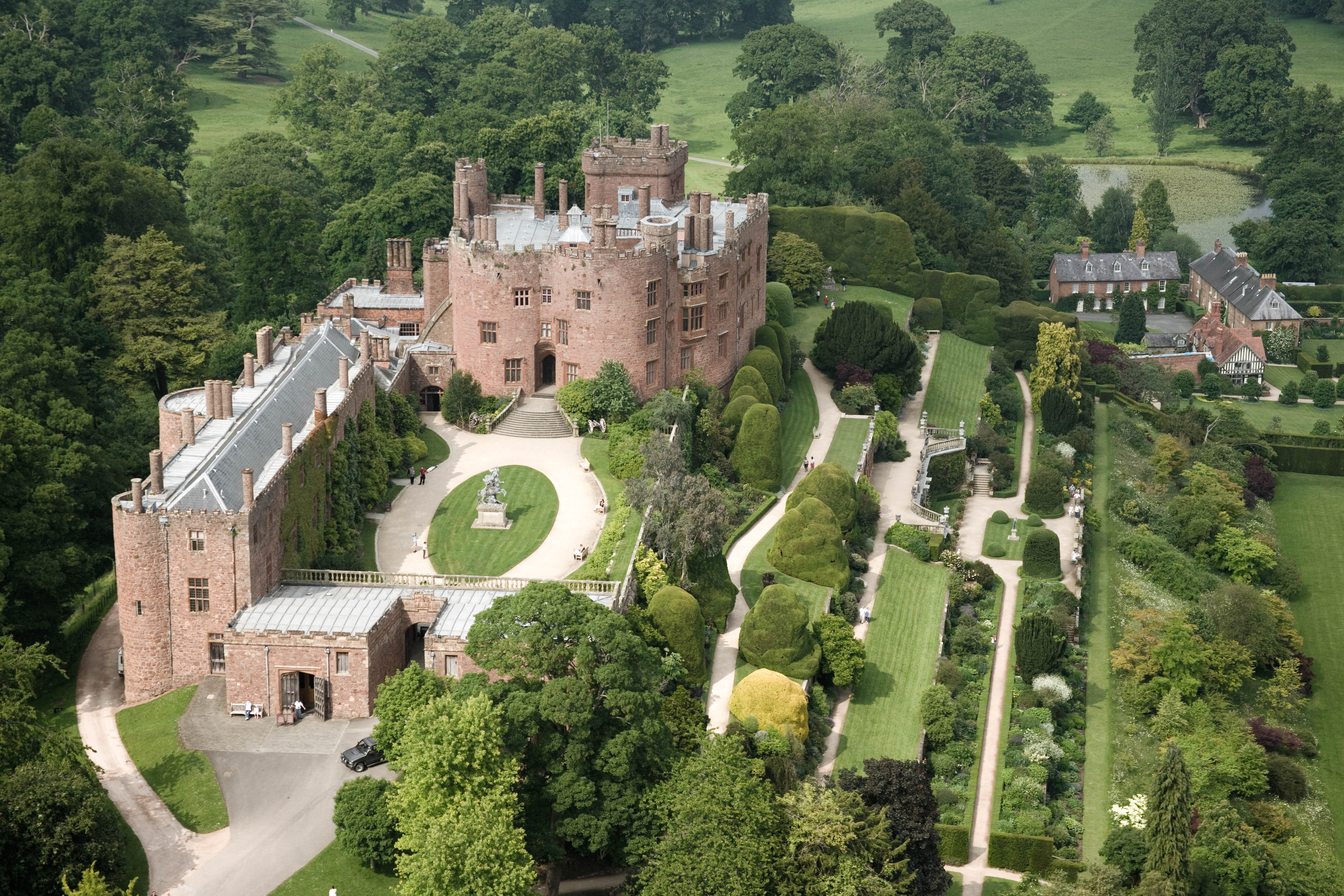 Aerial shot of a castle surrounded by acres of landscaped gardens.