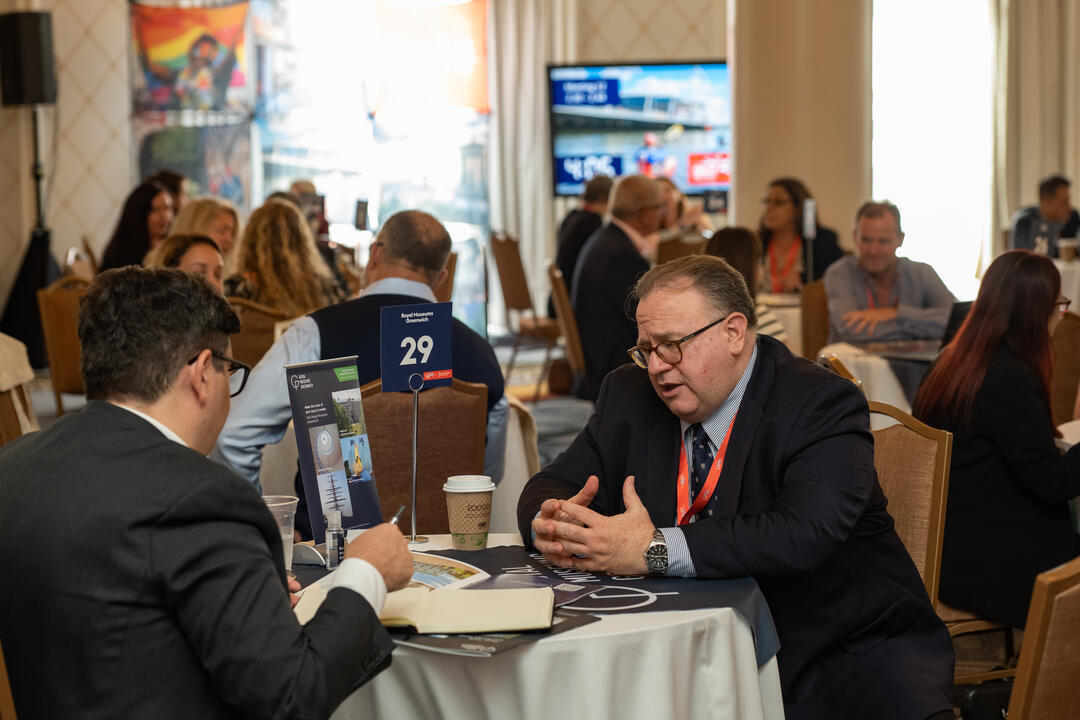 Attendees of an event sit at a table and talk