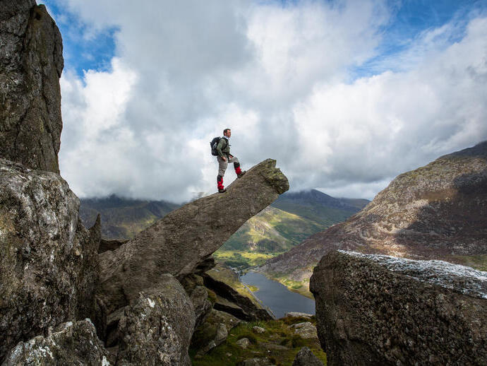 Mann, der auf einer hervorstehenden Felsformation steht und die Aussicht betrachtet