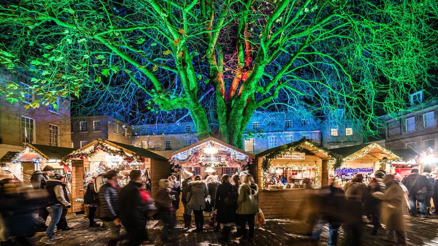 Des gens visitant les marchands du marché de Noël dans des chalets en bois à Bath
