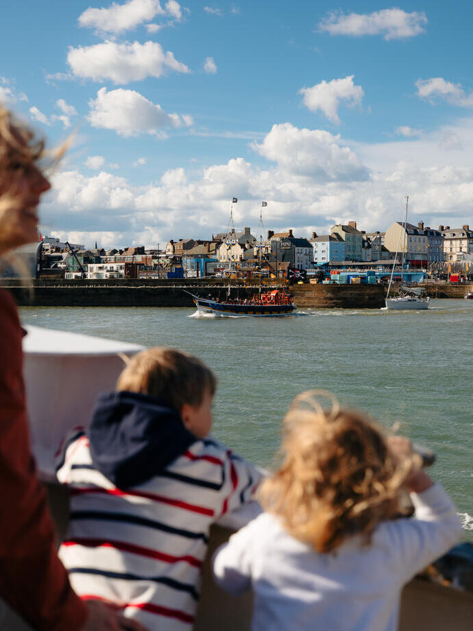 A family lean on a boat looking out to a harbour