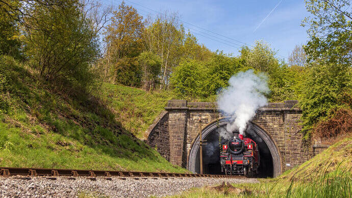 A steam train emerging from a tunnel