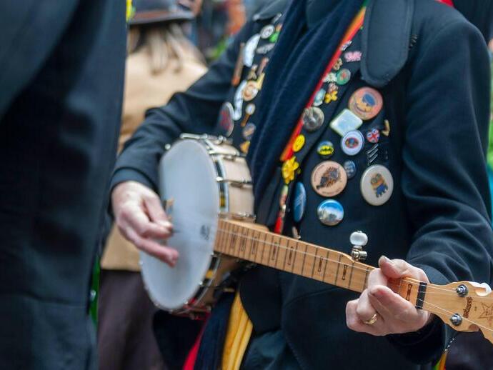 A folk player covered in badges at a music festival.