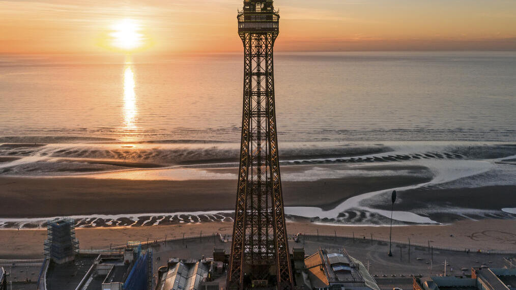 Torre alta al lado de la playa con la puesta de sol sobre el mar