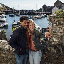 A couple taking a selfie using a smart phone while on holiday in Polperro, Cornwall.