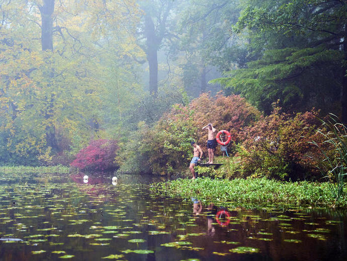 Dos hombres en la plataforma de un lago en un entorno otoñal