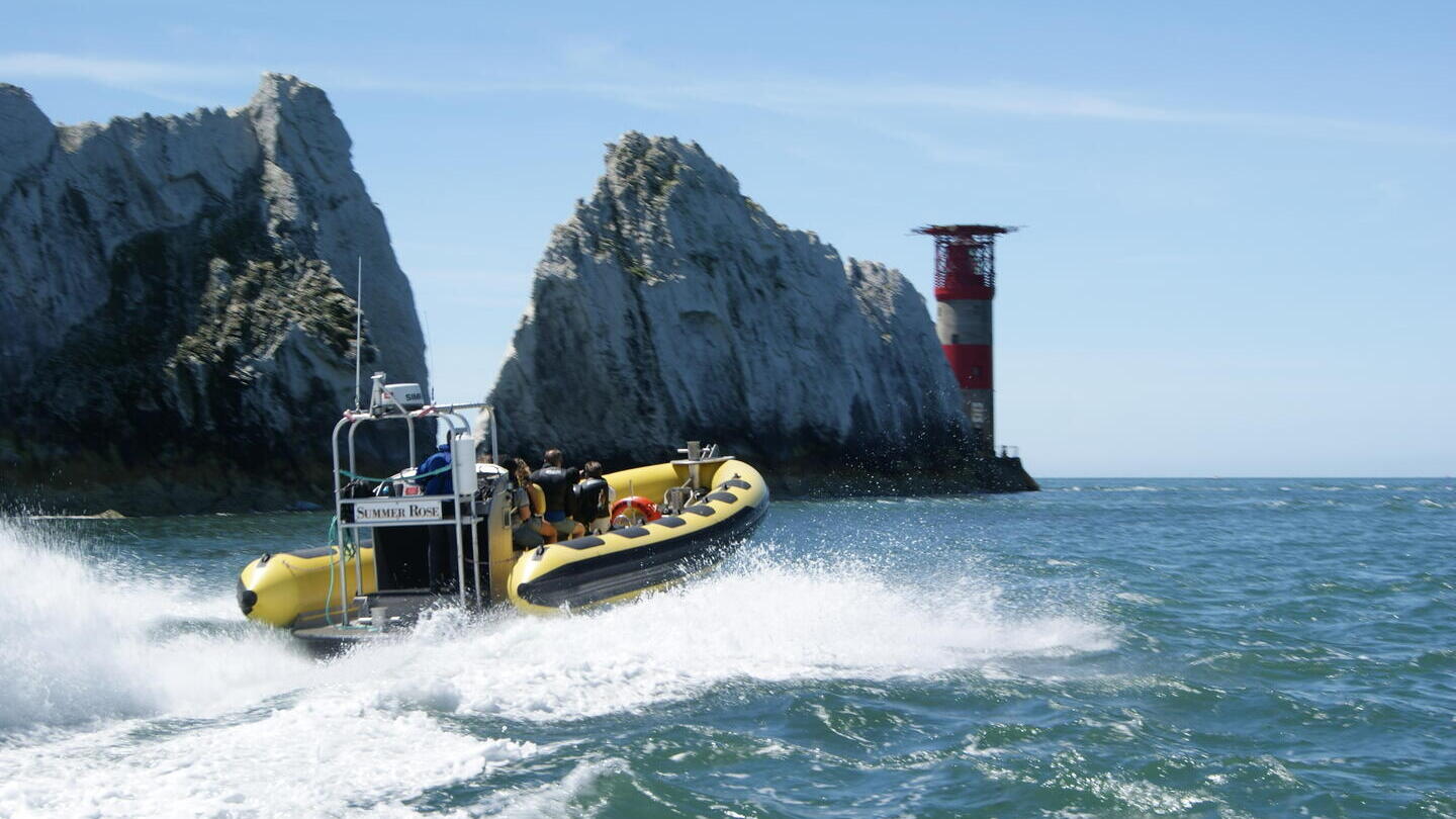 Boat passing chalk cliffs and a lighthouse