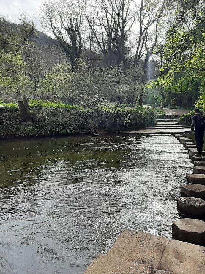 Man walking over stepping stones across a river