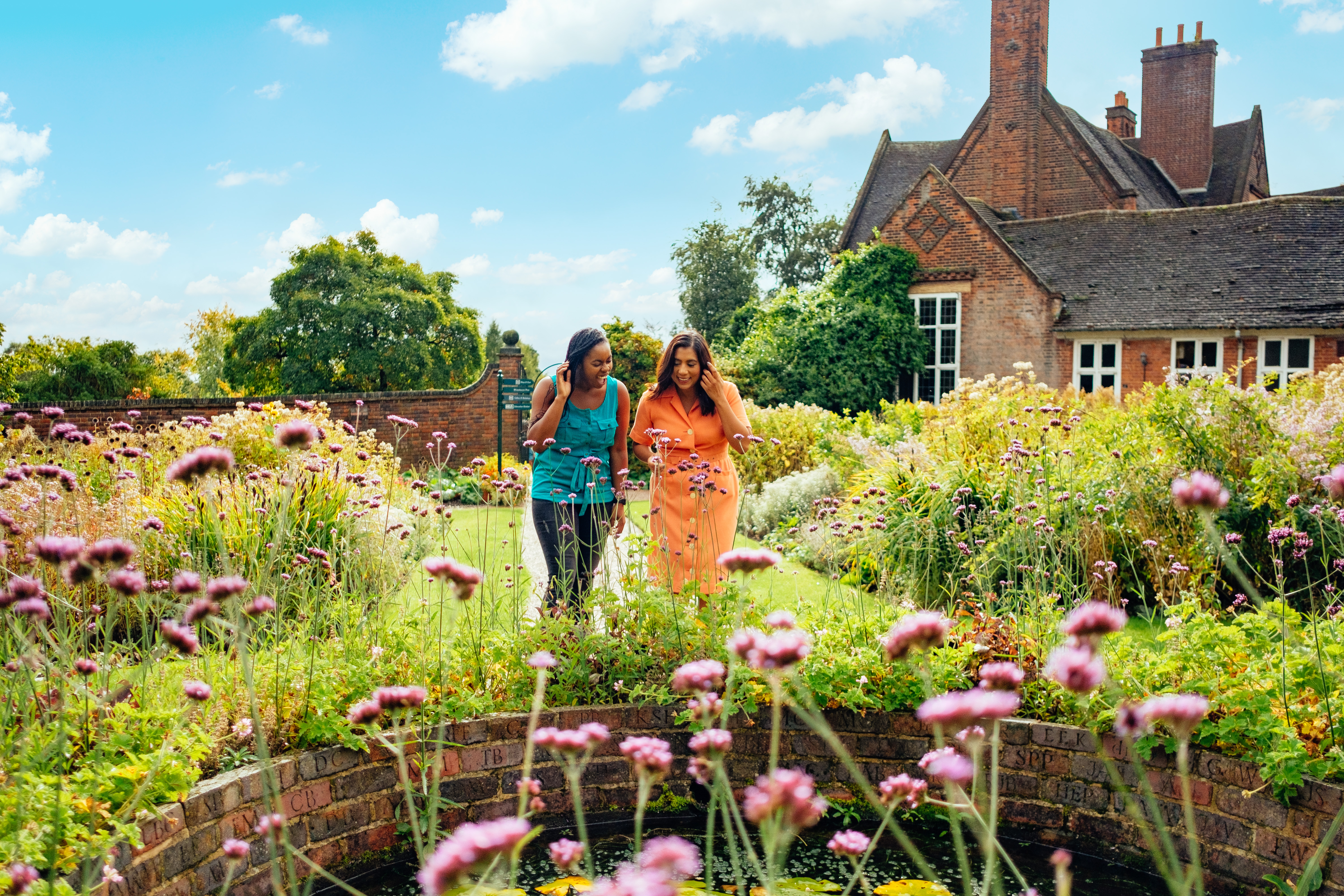 Two women walking through a garden filled with wildflowers