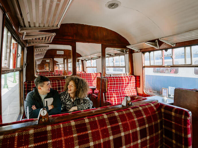 A man and a woman sitting together inside a train carriage.