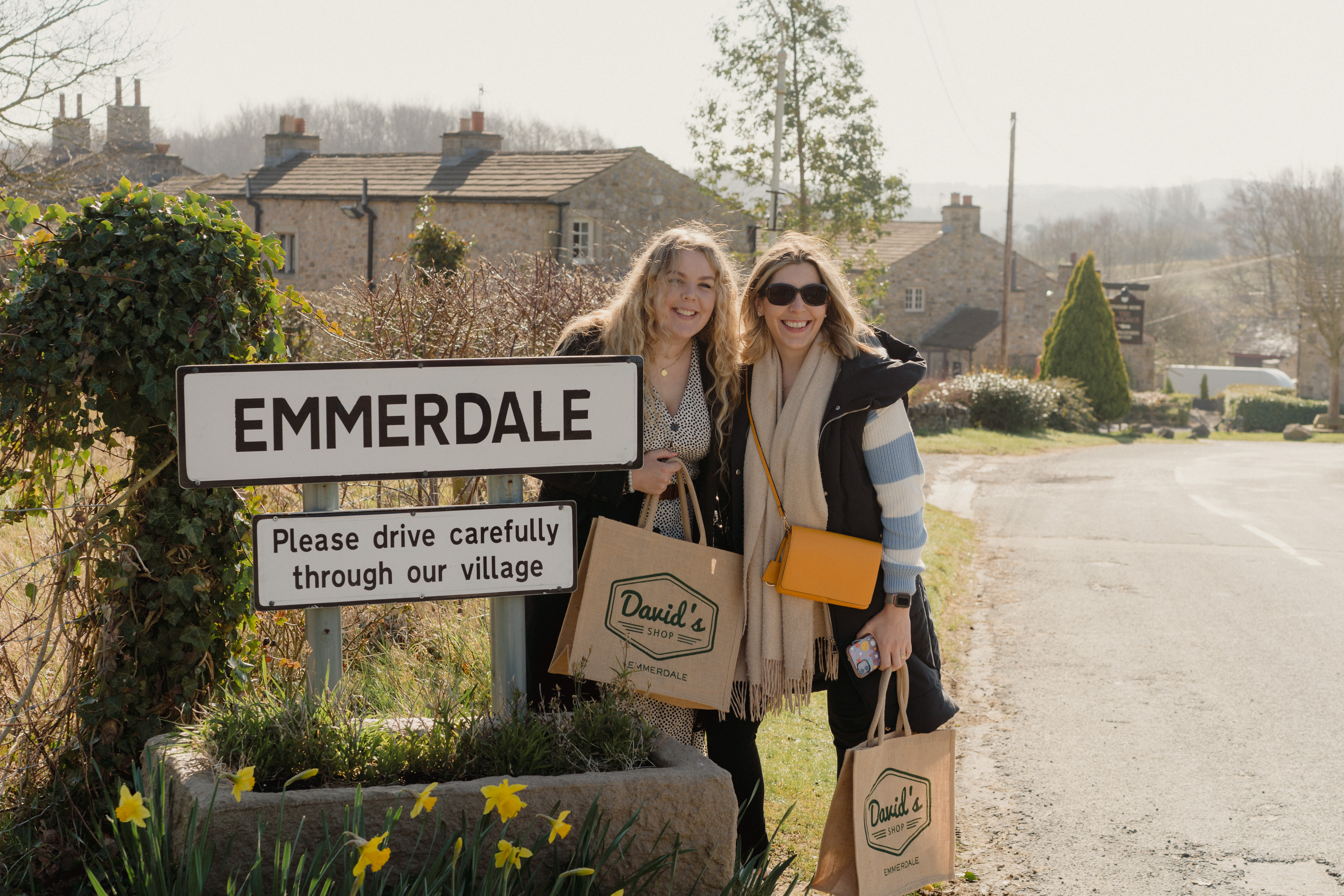 Two people posing outside the Emmerdale sign on a tour