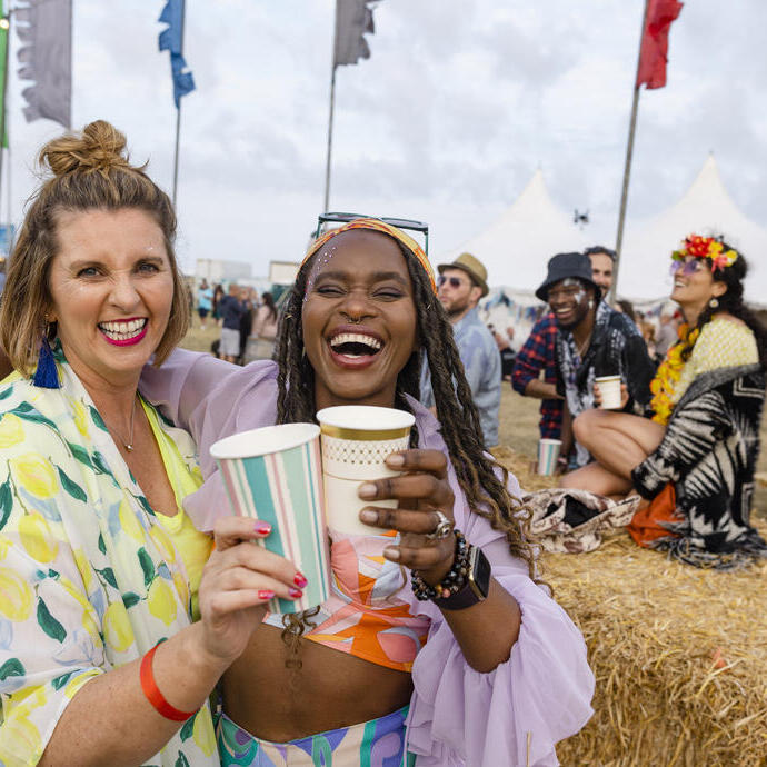 Zwei Frauen, die sich mit Freunden auf einem Festival amüsieren.