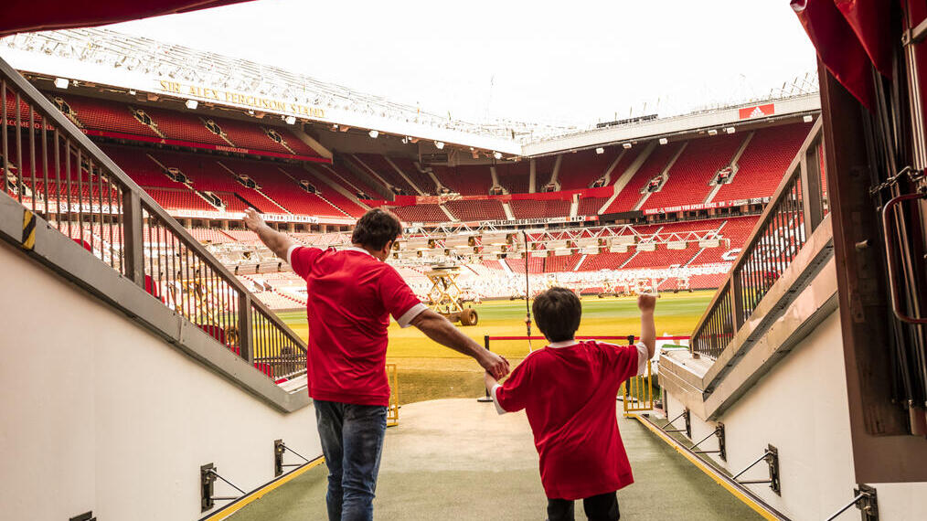 A man and boy in stadium tunnel looking out to pitch