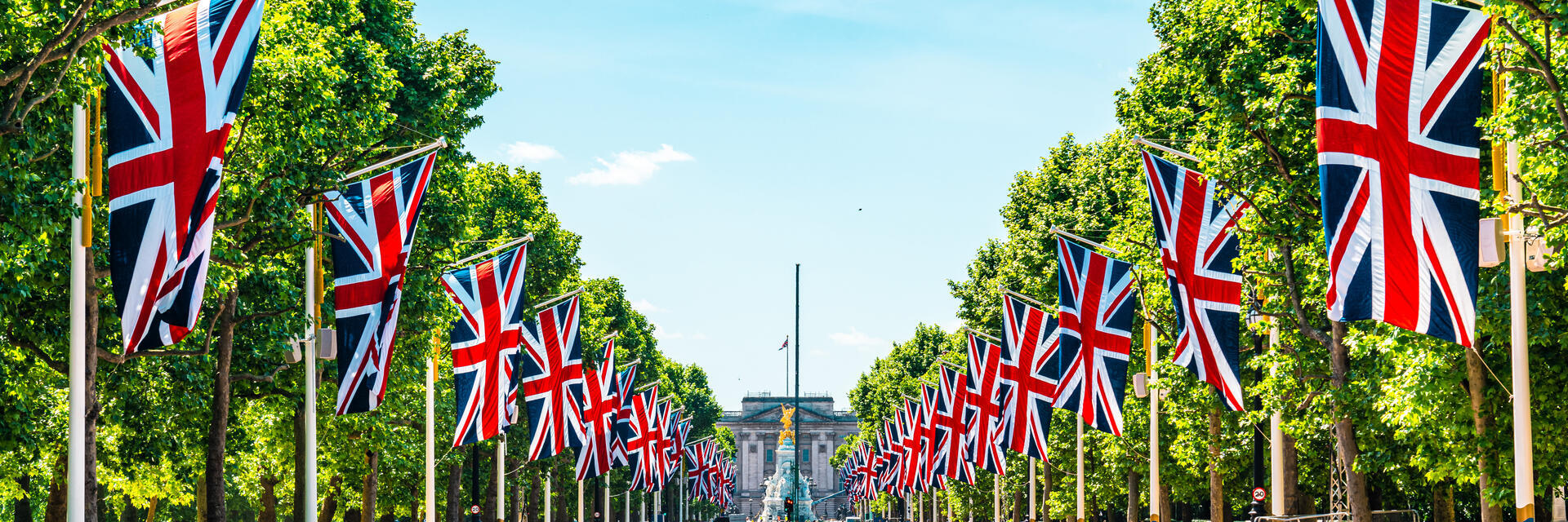 Allee mit Bäumen, die zu einem Palast mit Flaggen auf beiden Seiten führt