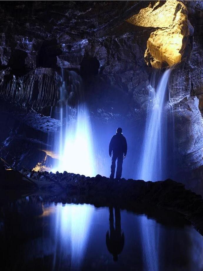 Uomo in piedi accanto a una cascata in una caverna buia