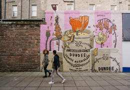 A man and a woman walking past the marmalade mural.