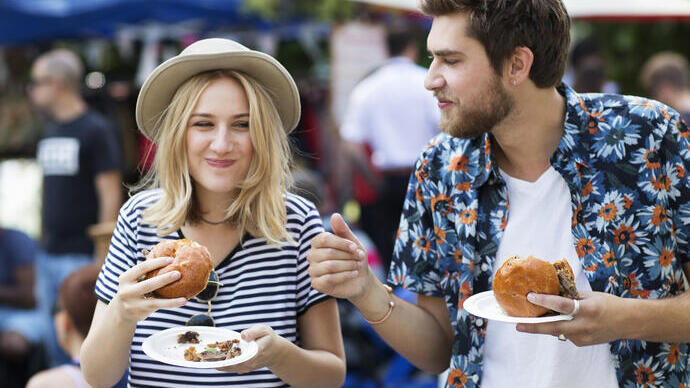 Couple mangeant des hamburgers au marché alimentaire.
