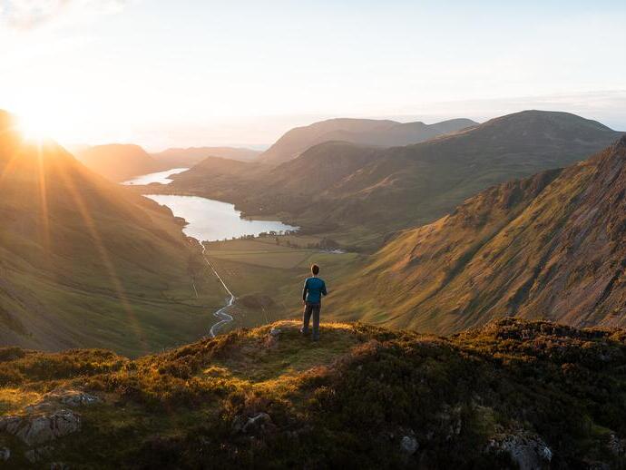 A man stands looking out over a vast lake view