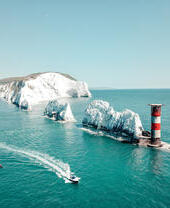 Tall chalk formations in a row running from the cliffs of the mainland to a lighthouse