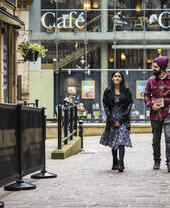 A woman and a man walk through a town centre