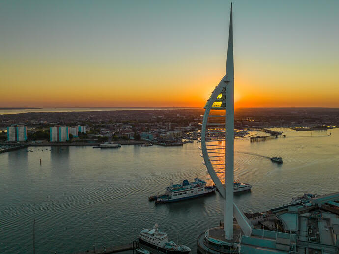 A modern tower next to the ocean at sunset