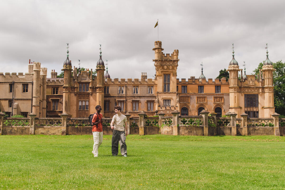 Two young men walk in the grounds of a heritage house