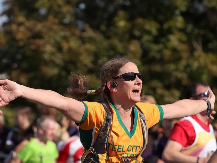 A woman celebrating while crossing the finish line on a run in Newcastle