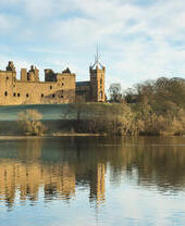 Esterno di una chiesa e di un castello in parte in rovina vicino a una città che si affaccia su un lago con cigni in inverno.