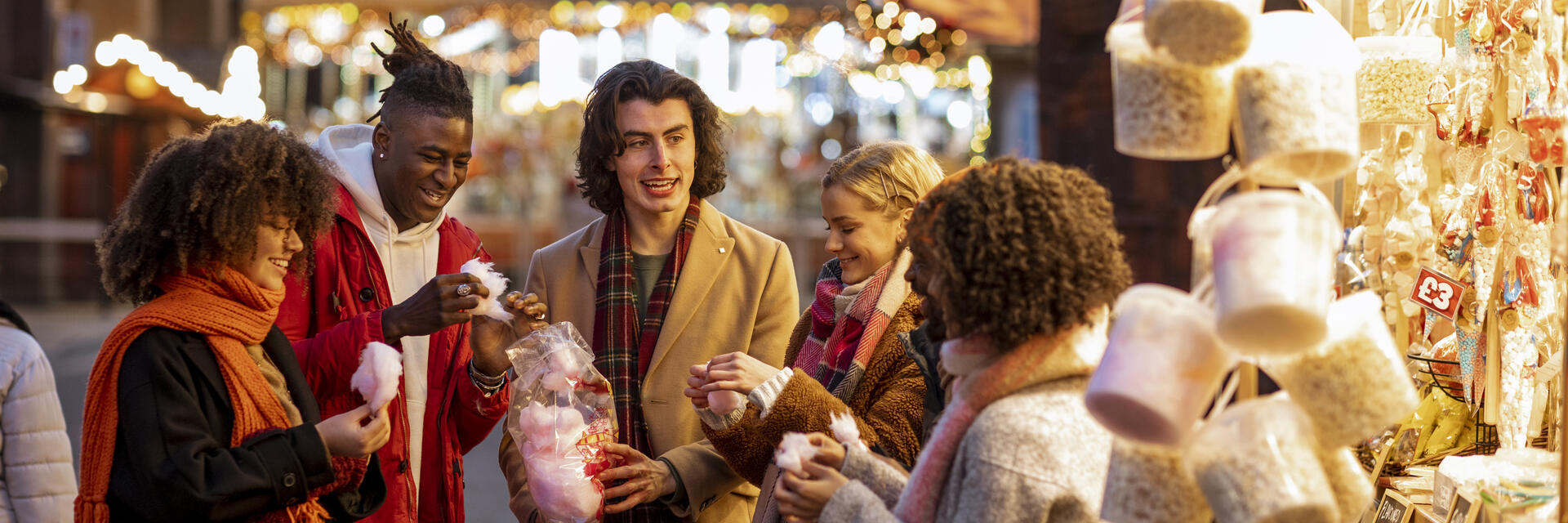 Groupe de jeunes amis partageant un sac de barbe à papa au marché de Noël.