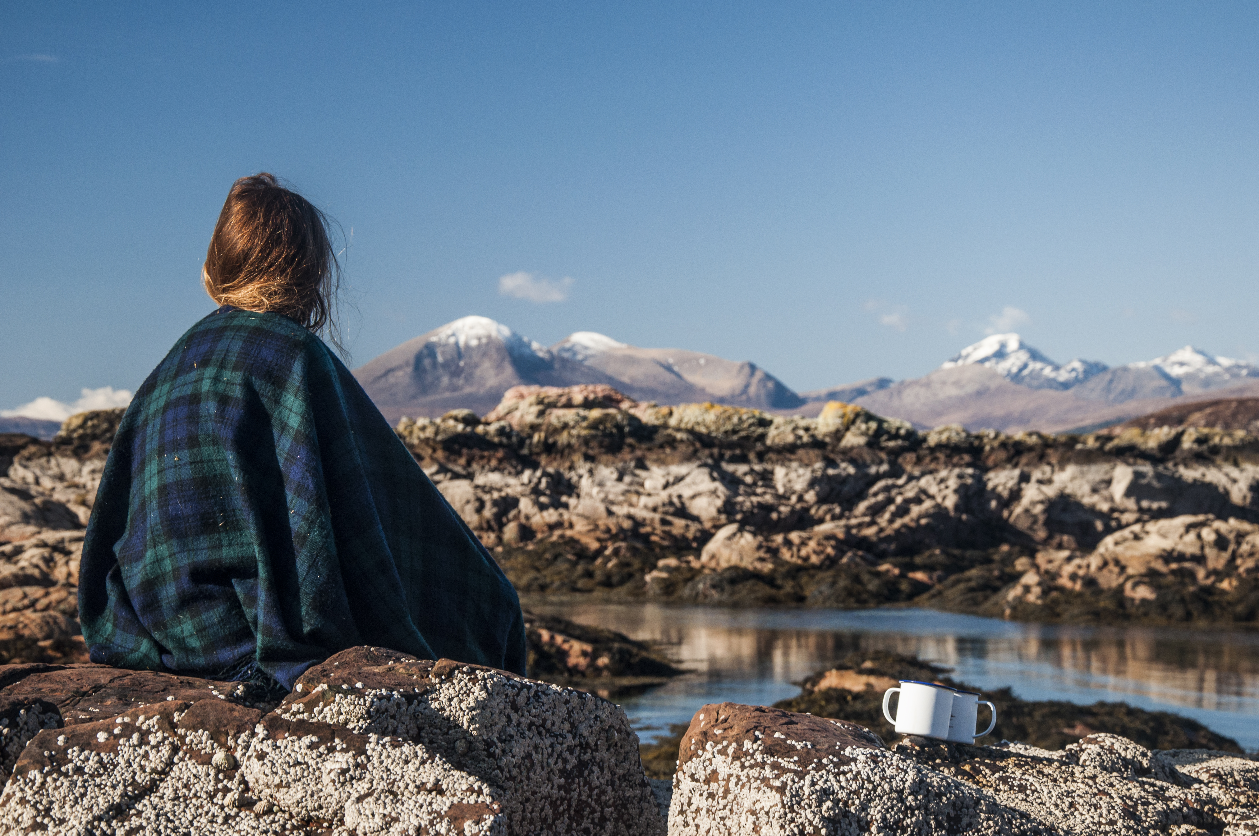 Woman sitting on a rock looking at the mountains in the distance