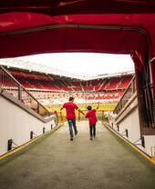 Un hombre y un niño en el túnel del estadio mirando hacia el campo