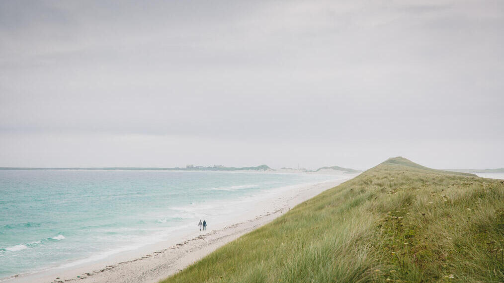 Two people walking along large empty beach, Tresness Sanday, Orkney