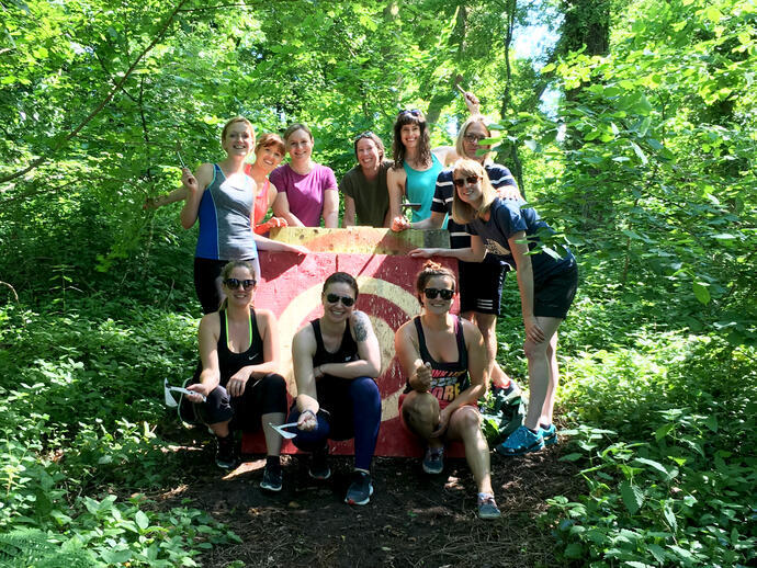 A group of people posing in front of a target at an axe throwing range in Bristol