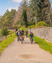A family with three boys cycles along a canal towpath.