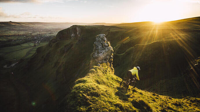 Cyclist riding down a steep hill at sunset
